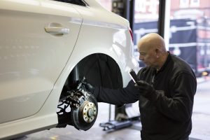 Mr Tyre technician inspecting brakes with wheel off
