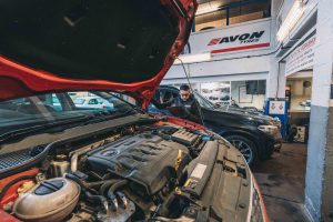 Mechanic performing under bonnet MOT checks.