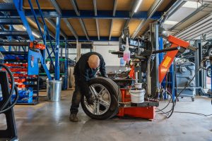 Mr Tyre Rochdale mechanic bending over to work on a tire and a rim